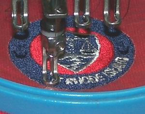 closeup of red shirt with embroiderd logo being stitched